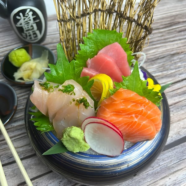 A colorful sashimi platter with tuna, salmon, and white fish, garnished with lemon and radish.