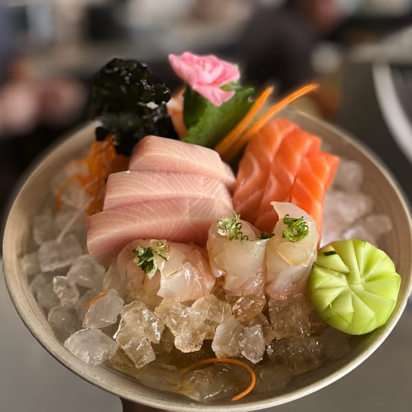 A Top Sushi sashimi platter with tuna, salmon, and white fish, garnished with a pink flower.